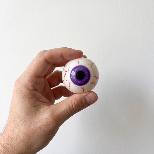 BLINK, the violet eyeball squishy, held in an adult hand